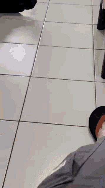 a person is standing on a tiled floor in front of a table .
