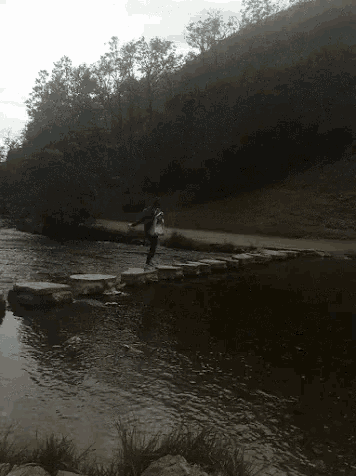 a person is crossing a river on a stone bridge