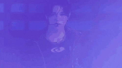 a young man is standing on a stage with a microphone in his mouth and looking at the camera .