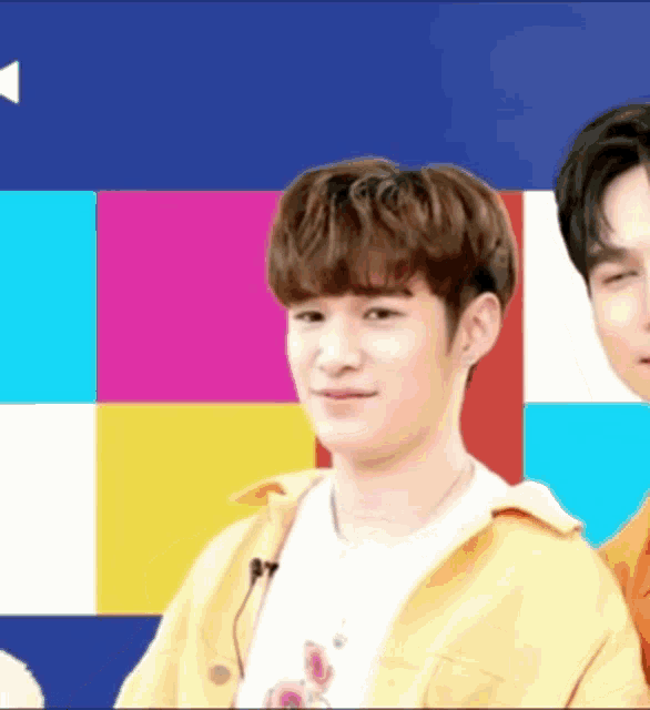 two young men are standing next to each other with a colorful background behind them .