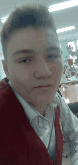 a young man wearing a white shirt and a red vest