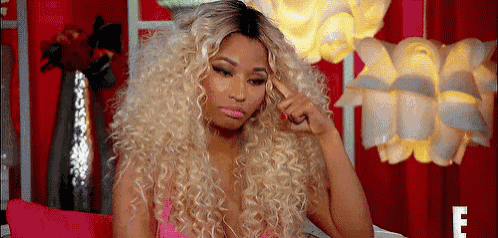 a woman with blonde curly hair is sitting on a couch and thinking .