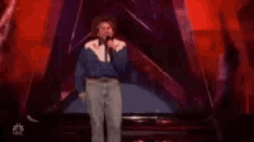 a man in a cowboy hat is singing into a microphone on a stage with two women .