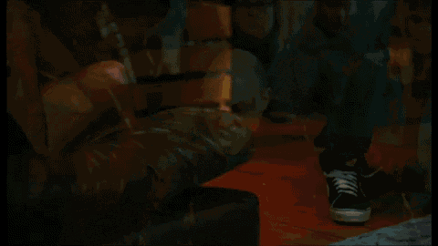 a group of people are standing around a man in a leather jacket with blood on his face