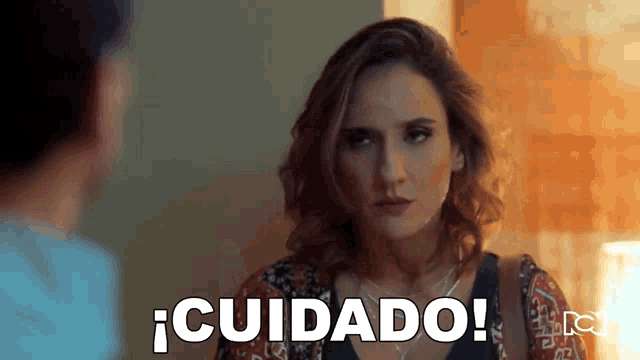 a woman is talking to a man in a room and says cuidado !