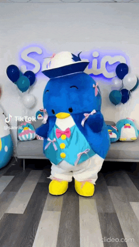 a stuffed animal in a penguin costume is standing in front of a couch and balloons .