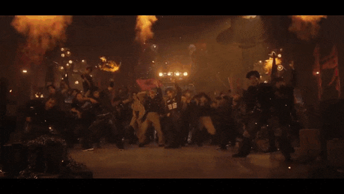 a group of people are dancing in front of a large explosion .