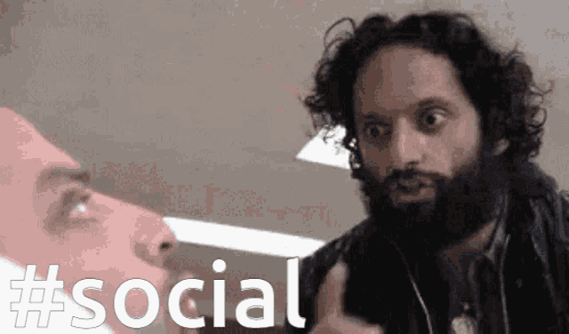 a man with a beard is pointing at another man with the words #social written below him
