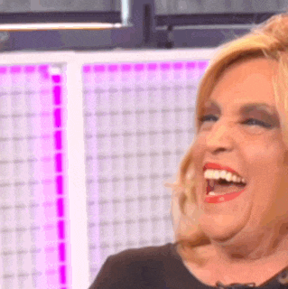 a woman is laughing with her mouth open in front of a pink background .