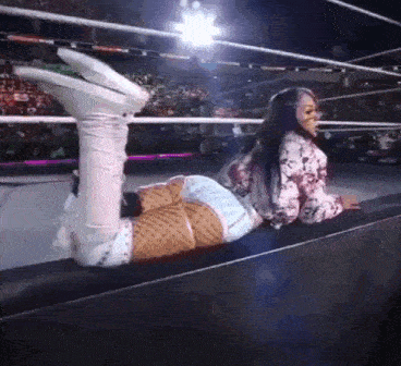 a woman is laying on the edge of a wrestling ring with her feet up .