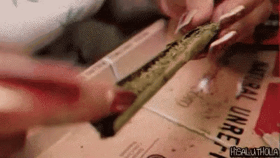 a woman is rolling a marijuana joint on a box .