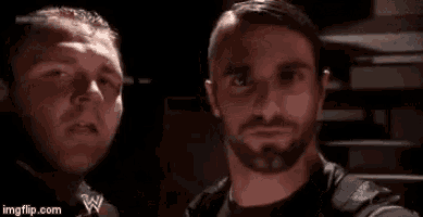 two men are standing next to each other in a dark room and smiling .