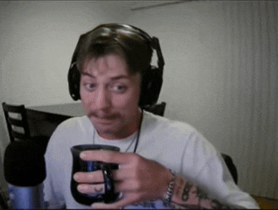 a man wearing headphones is holding a coffee mug in front of a microphone