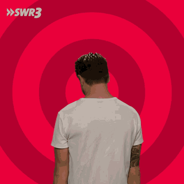 a man in a white shirt is making a funny face in front of a pink swirl with swr3 written on it