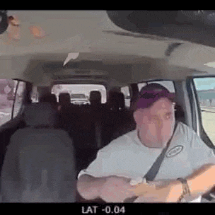 a man in a white shirt and purple hat is driving a car .