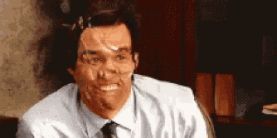 a man with tape on his face is smiling while sitting at a desk .