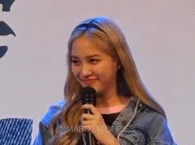 a woman is holding a microphone and smiling while wearing a headband .