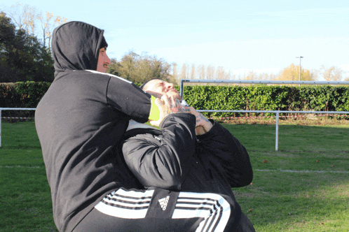 a man wearing adidas pants is holding another man 's head