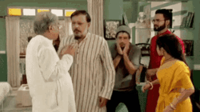 a group of people are standing around talking to each other in a room .
