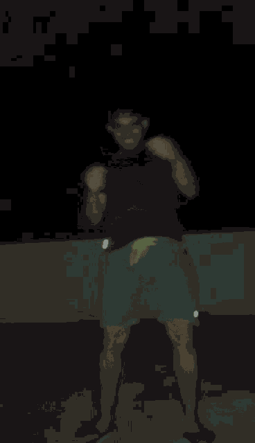 a man in a black shirt and green shorts is dancing at night