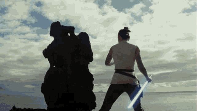 a woman holding a light saber stands next to a rock