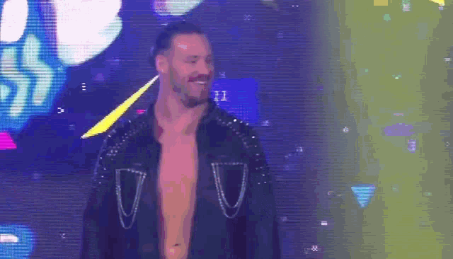 a man without a shirt is standing on a stage in front of a screen .