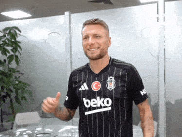 a man wearing a black beko shirt is giving a thumbs up