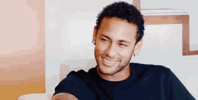 a man is smiling while sitting on a couch in a living room .
