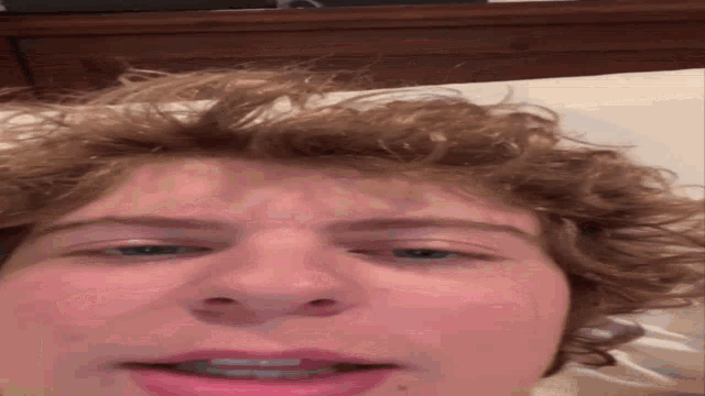 a young man with curly hair is laying on a bed