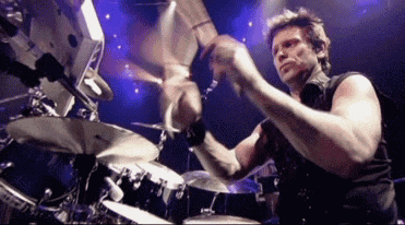 a man is playing drums on a stage with a camera behind him
