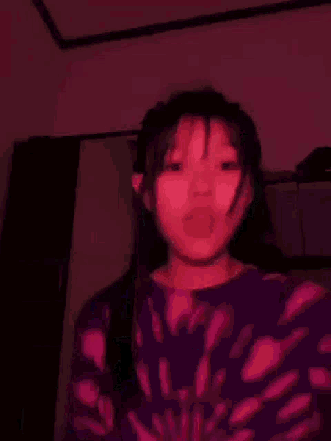 a girl in a purple tie dye shirt is giving a thumbs up .