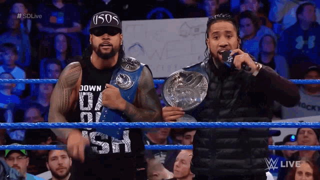 two men in a wrestling ring one of whom is wearing a shirt that says usos