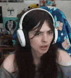 a woman wearing headphones is sitting in front of a computer screen .