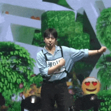 a man in a blue shirt and suspenders is dancing on a stage in front of a green background .