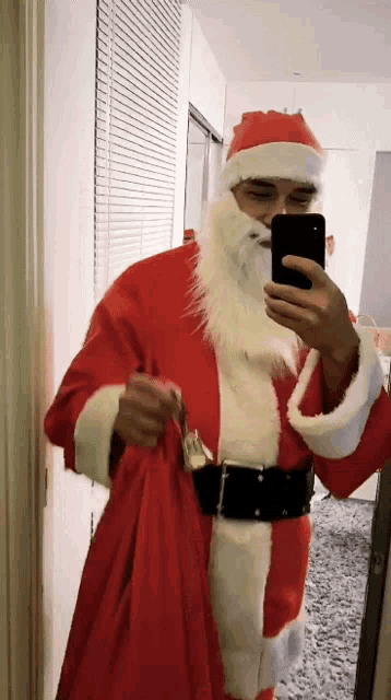 a man dressed as santa claus taking a selfie with his phone