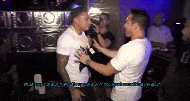 two men are standing next to each other in a dark room and one of them is asking the other what 's up my guy