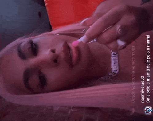 a woman with pink hair is wearing a necklace that says " venezuela "
