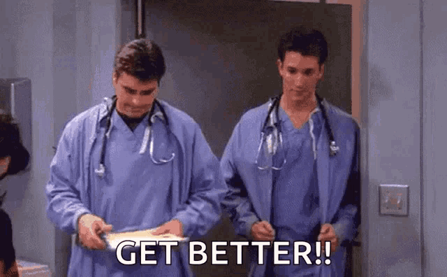 two doctors are standing next to each other in a hospital room holding a piece of paper that says get better .