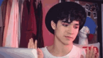 a young man wearing a black hat and a white shirt is looking at a tablet .