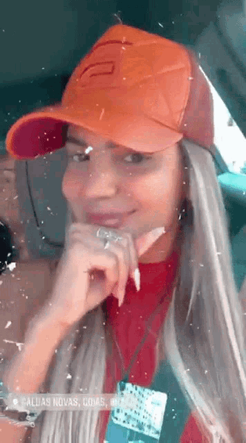 a woman wearing an orange hat is sitting in a car and smiling