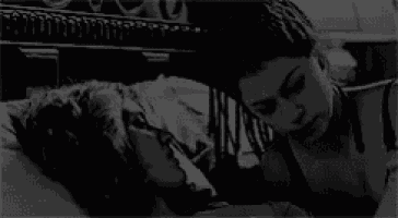 a couple of women are laying on a bed and kissing .