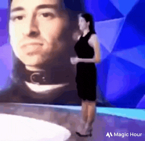 a woman in a black dress is standing in front of a picture of a man .
