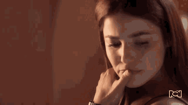 a close up of a woman 's face with her hand on her face .