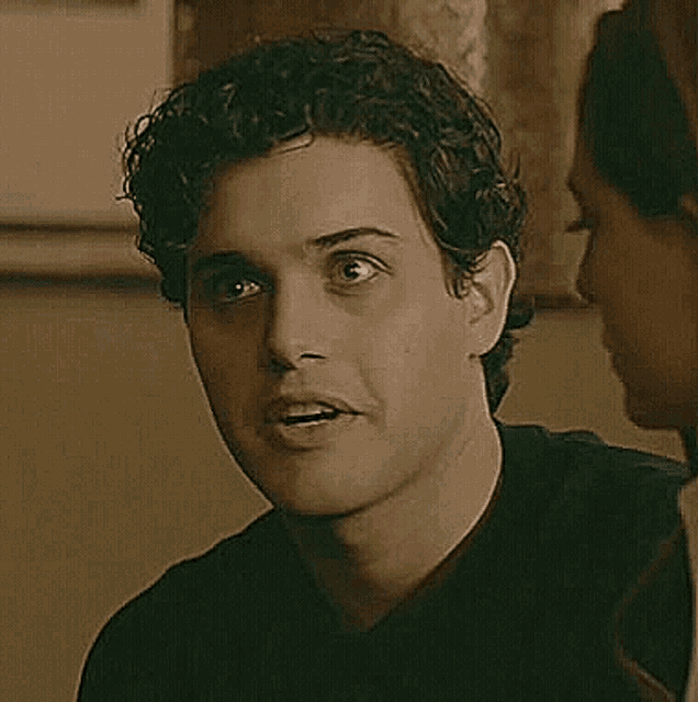 a man with curly hair is talking to a woman while looking at her .