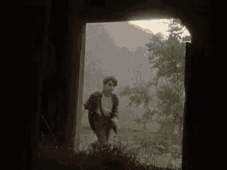 a man is walking through a doorway in a field .