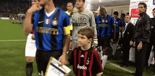 a boy wearing a black and red bwin jersey stands next to a group of soccer players