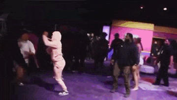 a woman in a pink hoodie is dancing in a crowded room .