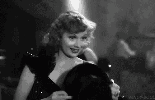 a black and white photo of a woman in a dress holding a bowling ball .