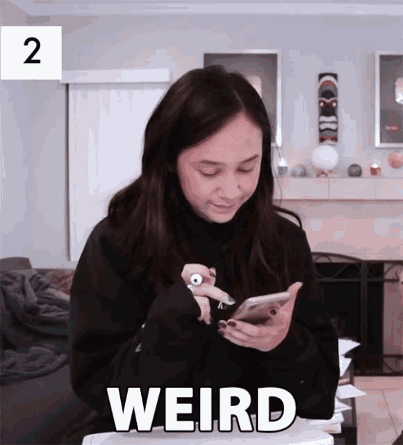 a woman is looking at her phone and the word weird is on the bottom