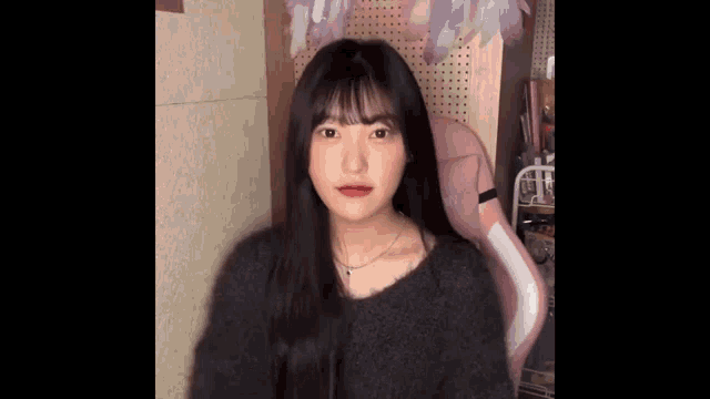 a young girl is sitting in a pink chair in a room and looking at the camera .